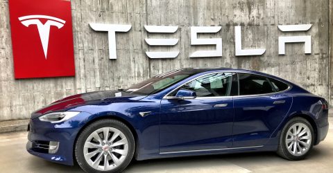 Dark Blue Tesla Electric Vehicle Parked under Tesla signage