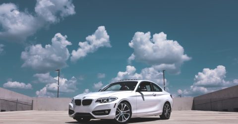 White BMW parked on conrete under blue skies with clouds